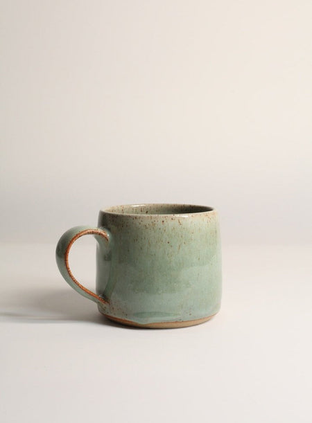 Green ceramic mug on a light grey background