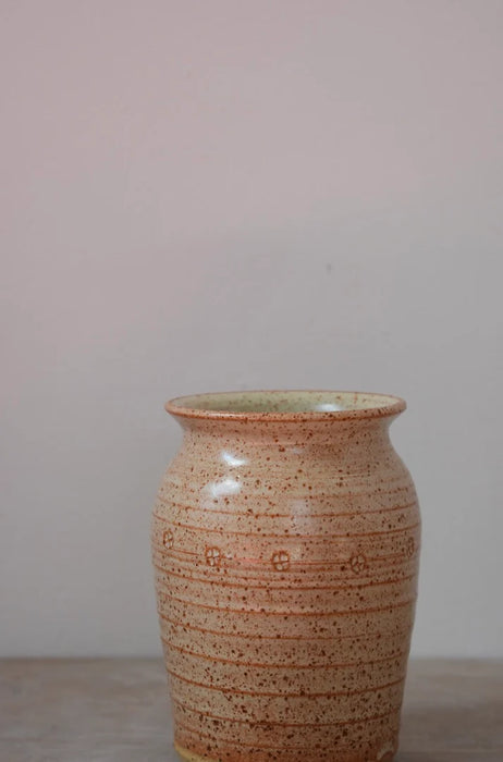 Ceramic vase with speckled brown and beige pattern on a plain grey background
