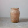 Ceramic vase with speckled brown pattern on a plain grey background