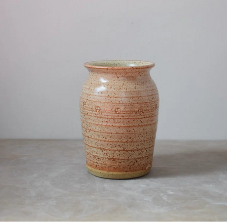 Ceramic vase with speckled brown pattern on a plain grey background