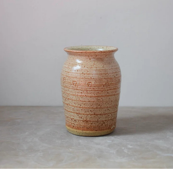 Ceramic vase with speckled brown pattern on a plain grey background
