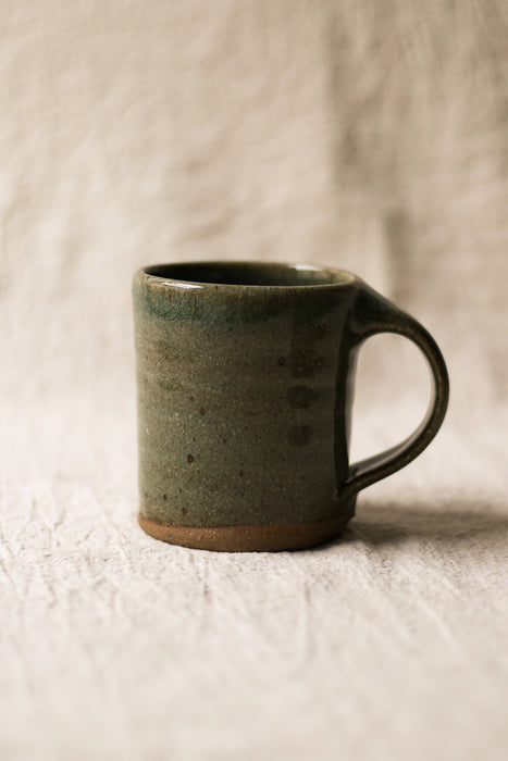 Green ceramic mug on a textured beige surface