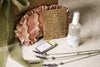 Herbal sleep sachet, bottle of pillow mist, pot of sleep balm, pink sleep mask, and lavender flowers on a beige linen surface.