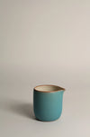 Turquoise ceramic jug with on a grey background