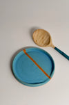 turquoise spoon rest with a carved wooden spoon next to it, on a white surface 
