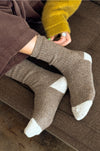 Person wearing brown wool socks , sitting on a brown sofa.