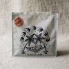 coffee bag with black palm tree design and 'Yallah' text on a textured beige linen background