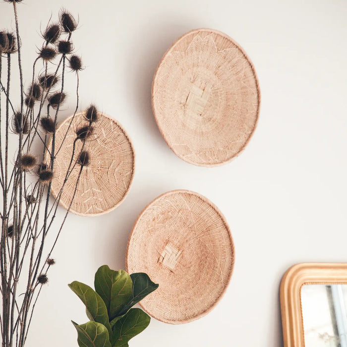 Three wooden baskets on a wall with dried plants and a mirror.