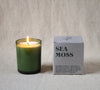 Green candle with 'Sea Moss' packaging on a neutral background