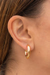 Close up of a persons ear wearing gold hoop earrings 
