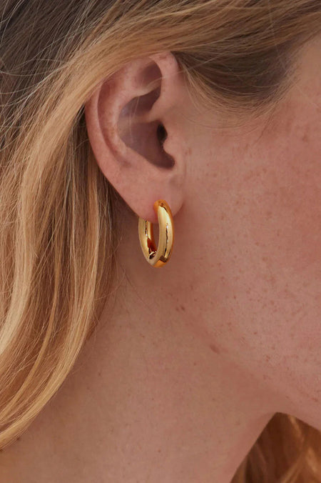 Close up of a persons face wearing gold hoop earrings