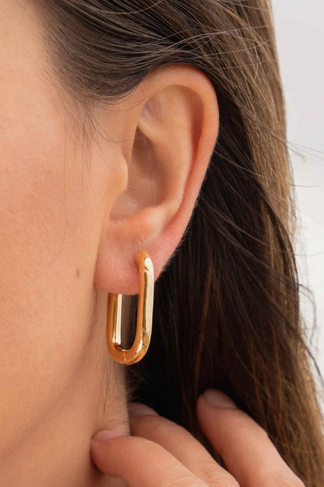 Close up of a models ear wearing gold hoop earrings 