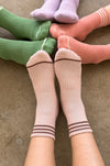 4 people wearing matching socks in various colours with feet touching 