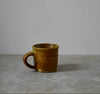 Brown ceramic mug on a grey surface with a plain white background