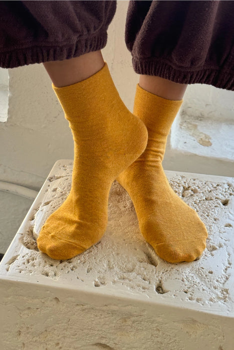 person wearing yellow socks and brown trousers