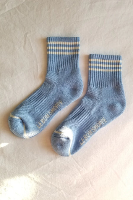 A pair of blue ankle socks with white stripes, displayed on a flat surface.