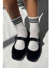 Black shoes and white socks with navy stripes on a light background