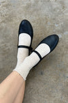 person wearing oatmeal socks with black mary-jane shoes