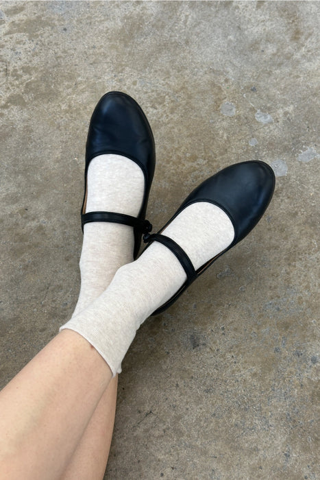 person wearing oatmeal socks with black mary-jane shoes