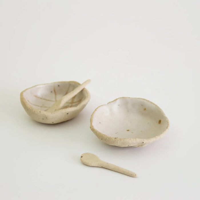 Two ceramic bowls with spoons on a light background